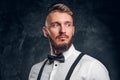 Closeup portrait of a man with stylish beard and hair in shirt with bow tie and suspenders. Studio photo against dark Royalty Free Stock Photo