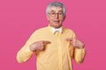 Closeup portrait of man in yellow shirt, asks question, poses in studio. Isolated over pink background. Tempered human emotions. Royalty Free Stock Photo