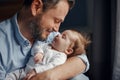 Closeup portrait of middle age bearded Caucasian father hugging and kissing newborn baby. Male man parent holding child. Authentic Royalty Free Stock Photo