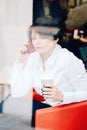 Closeup portrait of middle age Caucasian white business woman sitting in cafe restaurant with cup of coffee talking over on phone Royalty Free Stock Photo