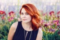 Closeup portrait of middle aged white caucasian woman with waved curly red hair in black dress looking in camera