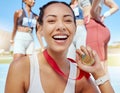 Closeup portrait of mixed race athletic woman showing gold medal from competing in sports event. Smiling fit active