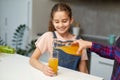 Closeup portrait of a mom pours her cute daughter orange juice for breakfast. Royalty Free Stock Photo