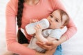 Closeup portrait of mother with baby on hands, little child holding bottle and drinking milk at home Royalty Free Stock Photo