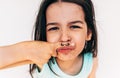 Closeup portrait of the naughty little girl makes grimace with mustache drawing on her index finger put it under the nose. Cute Royalty Free Stock Photo