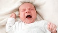 Closeup portrait of newborn baby crying and screaming while lying in crib Royalty Free Stock Photo