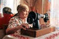 Closeup portrait of old woman using sewing machine, 70 years seamstress working at home Royalty Free Stock Photo