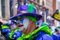 Closeup portrait of an older man with colorful face paint and a purple hat dressed up for the Mummers Parade