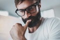 Closeup portrait of pensive bearded designer wearing eye glasses and working at the modern lightful office loft Royalty Free Stock Photo