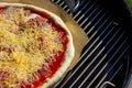 A closeup portrait of a pizza being baked on a piece of baking paper on a pizza stone on a barbecue grill. The pizza is topped Royalty Free Stock Photo