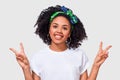 Closeup portrait of positive African American young woman smiling broadly, showing peace gesture while looking to the camera, Royalty Free Stock Photo