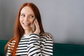 Closeup portrait of positive young woman talking on mobile phone at home. Cheerful redhead female making answering call Royalty Free Stock Photo