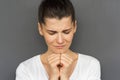 Closeup portrait of praying young female with dark hair holding her hands together at the chin, being concentrated on her wish. Royalty Free Stock Photo