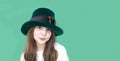 A closeup portrait of preteen girl in St. Patrick& x27;s Day hat on green backgroundwhite. Copy space Royalty Free Stock Photo