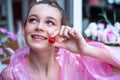 Closeup portrait pretty dreaming, enigmatic teenage girl face with smile in pink raincoat looking up. tasting raspberry Royalty Free Stock Photo