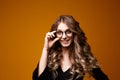 Closeup portrait of pretty yong woman with bright makeup in a glasses isolated over the yellow background. Royalty Free Stock Photo
