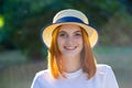 Closeup portrait of redhead hipster teenage girl in yellow hat smiling outdoors in sunny summer park Royalty Free Stock Photo