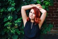 Closeup portrait of relaxing middle aged white caucasian woman with waved red hair in black dress looking in camera Royalty Free Stock Photo