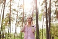 Closeup portrait of relaxing woman dresses casual striped shirt, listening to music in forest in open air, keeping hands on her Royalty Free Stock Photo