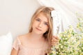 Closeup portrait of a romantic charming young blonde with long hair. Little girl and daisies on bed in a bright bedroom in morning