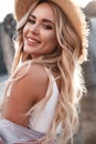 Closeup portrait of a romantic young woman in a straw hat. Laughing girl enjoying her time outside in park with sunset in backgrou