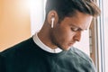 Closeup portrait of sad young handsome man speaking with a friend using wireless earphones. Royalty Free Stock Photo