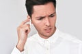 Closeup portrait of sad young handsome man wearing white shirt and speaking with a friend using wireless earphones. Royalty Free Stock Photo