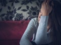 Closeup portrait of sad young woman sitting by sofa at home. Royalty Free Stock Photo