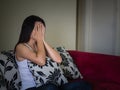 Closeup portrait of sad young woman sitting by sofa at home. Royalty Free Stock Photo