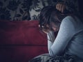 Closeup portrait of sad young woman sitting by sofa at home. Royalty Free Stock Photo