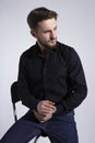 Closeup portrait of a seated bearded young man looking at the side on white background