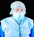 Closeup portrait of serious doctor in protective face mask, goggles and disposable surgical cap with stethoscope. Male Royalty Free Stock Photo