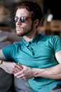 Serious man with moustage and beard wearing sunglasses and sitting at airport