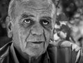 Closeup portrait of a serious old greek retired male who smokes a cigarette with a smile, in black and white Royalty Free Stock Photo