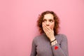 Closeup portrait of shocked attractive girl with curly hair covering mouth with her hand and looking away with frightened face Royalty Free Stock Photo