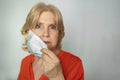 Closeup portrait shot of older woman taking off face mask