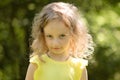 Closeup portrait of a skeptical little girl looking suspiciously, skeptical, half-smile, ironically. Portrait in green Royalty Free Stock Photo