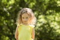 Closeup portrait of a skeptical little girl looking suspiciously, skeptical, half-smile, ironically. Portrait in green