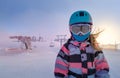 Closeup portrait of skier girl wearing mask, helmet and googles in the snowy mountains