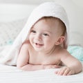 Closeup portrait of smiling baby boy lying on bed with towel on head after having shower Royalty Free Stock Photo