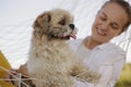 Closeup portrait of smiling beautiful cute Caucasian woman wearing white shirt lies in a hammock with Pekingese dog in nature, Royalty Free Stock Photo