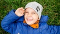 Closeup portrait of smiling cute boy lying on green grass on the field Royalty Free Stock Photo