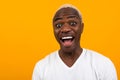 Closeup portrait of a smiling handsome black blond African man with grimace on orange background with copy space Royalty Free Stock Photo