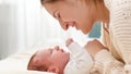 Closeup portrait of smiling loving mother stroking and looking on her newborn baby son lying on bed on bright sunny day Royalty Free Stock Photo