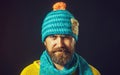 Closeup portrait of smiling man with beard in hat and scarf. Winter accessories. Handsome bearded man in yellow sweater