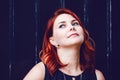 Closeup portrait of smiling middle aged white caucasian woman with waved curly red hair in black dress looking away Royalty Free Stock Photo