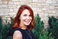 Closeup portrait of smiling middle aged white caucasian woman with waved curly red hair in black dress looking in camera Royalty Free Stock Photo