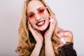 Closeup portrait of smiling young blonde in pink glasses, party photoshoot, confetti everywhere. Has beautiful smile Royalty Free Stock Photo