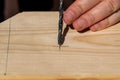 A closeup portrait of someone aiming and placing the tip of a wood drill bit at the drawn pencil marking made on a wooden plank to Royalty Free Stock Photo