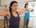 Hispanic woman doing warmup during group workout at gym